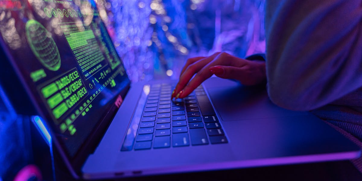 Hands typing on a laptop displaying cybersecurity protection graphics
